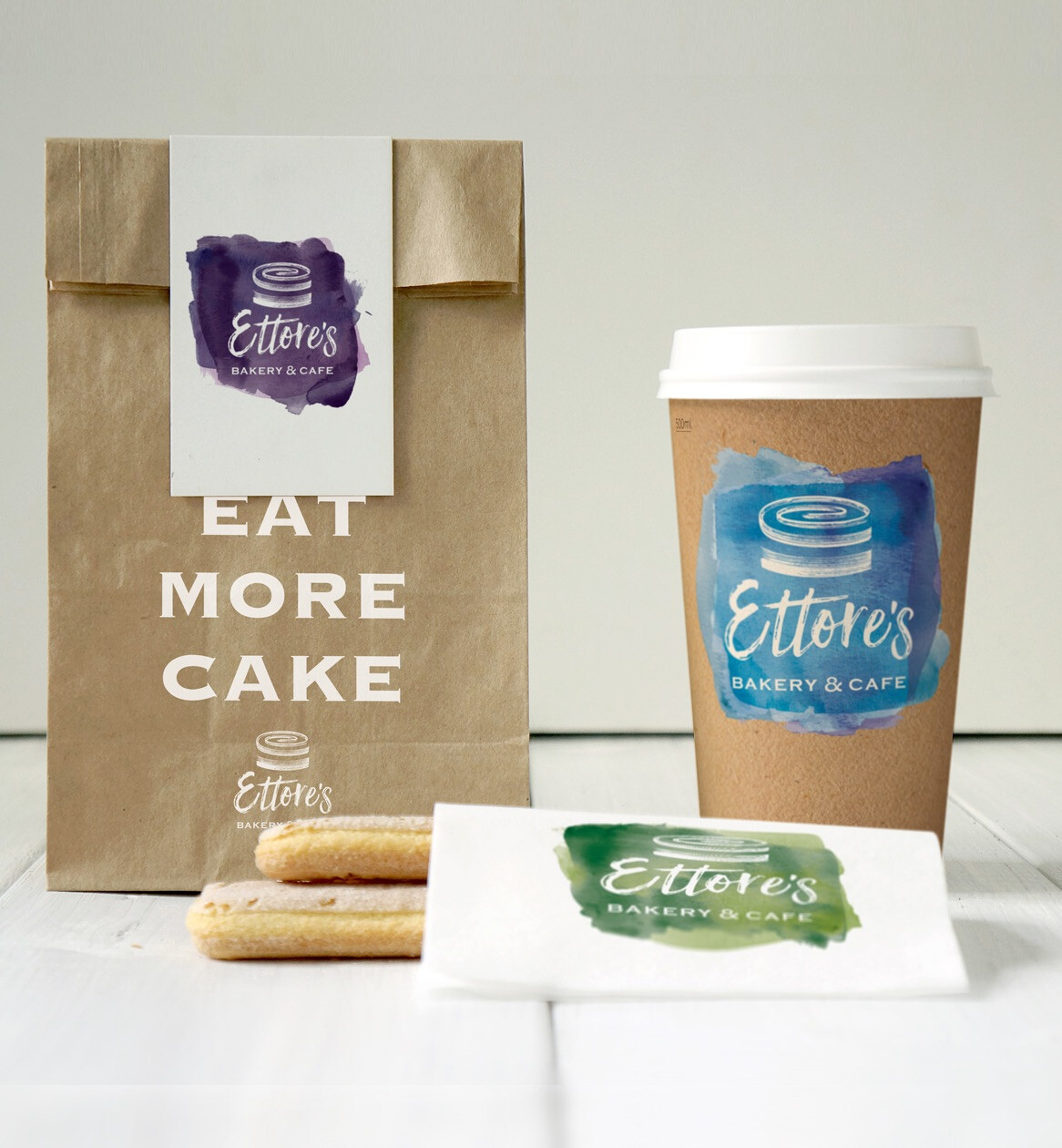 Brand concept imagery featuring the new logo on a takeaway bag, a coffee cup, and a food wrapper.
